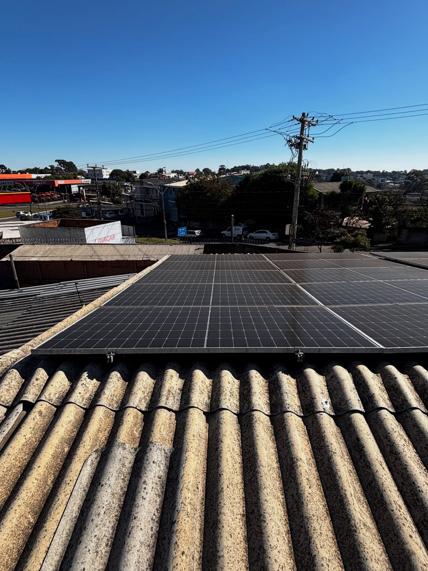 Painéis solares em telhado de fibrocimento com vista da cidade
